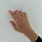 Hand wearing gold rings and a bracelet on a light background
