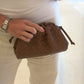 Person holding a brown quilted handbag with a white background