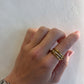 Hand wearing a gold ring on a light gray background