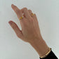 Hand wearing two gold rings on a white background