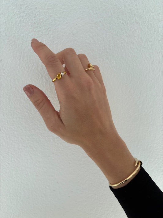 Hand wearing two gold rings on a white background
